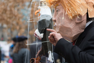A performer at McPherson Square peaceful protest uses a paper mache Donald Trump face and eagle to represent his feelings of oppression.