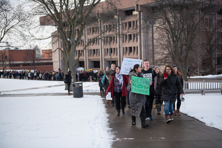 Arva Hassonjee (green sign) and Nedda Sarshar (megaphone) lead hundreds of students down Syracuse University's promenade on Thursday, Feb. 2, 2017 in a 